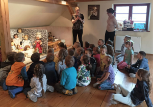 Dzieci słuchają opowieści pracownika muzeum na temat zabawek